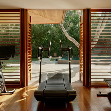 Two-bedroom pool villa at Amanyara with treadmill facing garden views through open wooden doors.