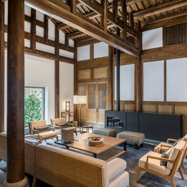 Antique villa living room at Amanyangyun with wooden latticed screens, traditional furnishings, and natural light from large windows.