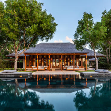 Wooden pavilion with reflection in still pool at Amanyara, surrounded by trees.