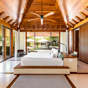 Bedroom 2 at Amanyara with wooden ceiling, platform bed, and garden views through open doors.