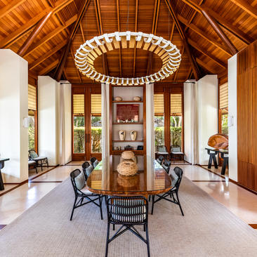 Bedroom 5 at Amanyara villa features a wooden vaulted ceiling, circular pendant light, and dining area with chairs.