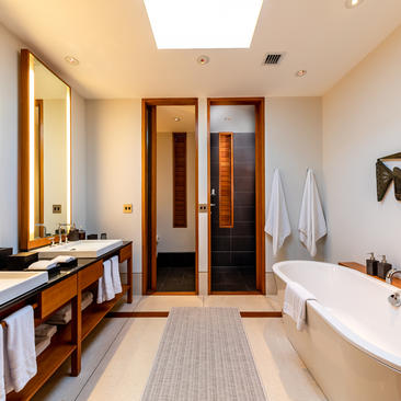 Spacious bedroom ensuite at Amanyara with dual vanities, wooden cabinetry, and freestanding bathtub.