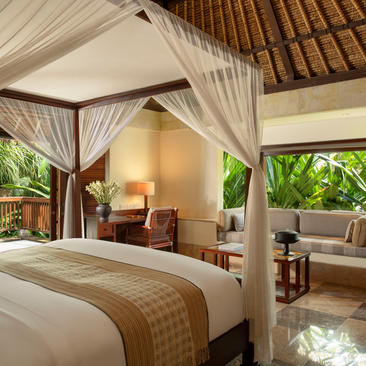 Principal bedroom with four-poster bed, wooden beams, and garden views at Aman Villas at Nusa Dua.