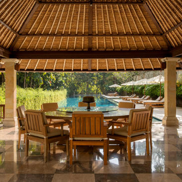 Dining pavilion at Aman Villas at Nusa Dua, with wooden teak ceiling, table seating, and ocean views.