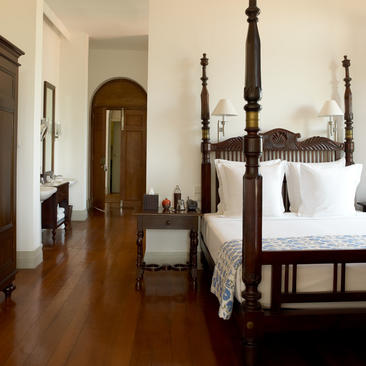 Principal bedroom at Amangalla with four-poster bed and wooden flooring.