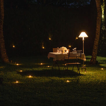 Candlelit outdoor seating area at night at Amangalla, with illuminated pathways through manicured grounds.