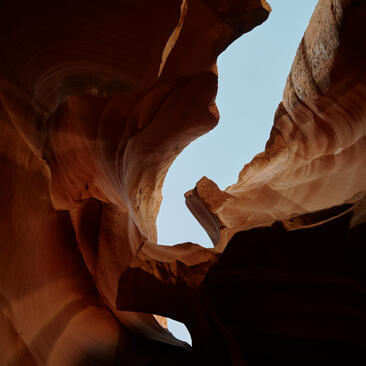Sunlight filters through towering red rock walls of a slot canyon at Amangiri.