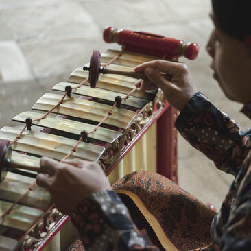 Hands playing a traditional gamelan instrument in Amanjiwo's lobby.