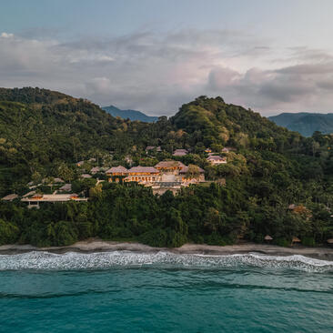 Amankila resort nestled among forested hillsides overlooking turquoise waters in Bali, Indonesia.