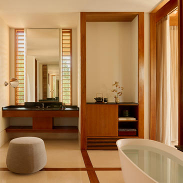 Ocean Cove Pavilion bathroom at Amanyara with wooden vanity, round pouffe and freestanding bathtub.