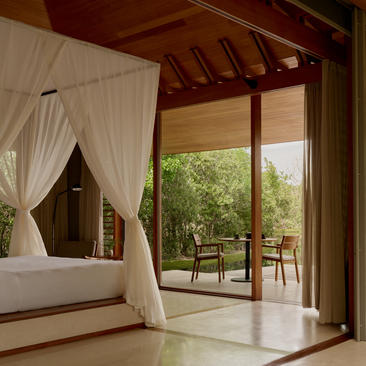 Tranquility Pavilion principal bedroom with canopied bed and open doors to garden at Amanyara.