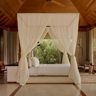 Tranquility Pavilion at Amanyara with draped cream curtains framing a bed and garden view.