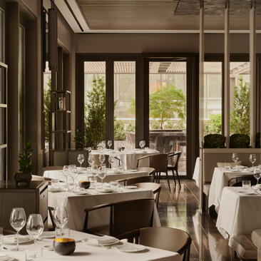 アマン ニューヨークのアルヴァレストランで、大きな窓から自然光が注ぐ、洗練されたダイニング空間。