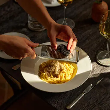 Tagliolini caseiro com trufa de verão preta e manteiga sendo finalizado na Aman New York.