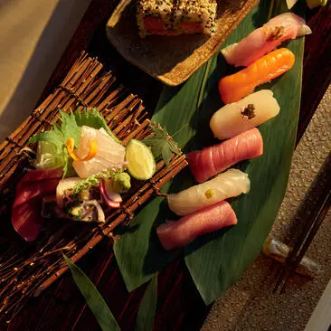 Prato de sushi nama no Aman New York, com ingredientes frescos dispostos em folha verde.