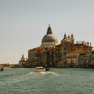 Basilica di Santa Maria della Salute and historic palaces along the Grand Canal at Aman Venice, with a water taxi passing through the waterway.