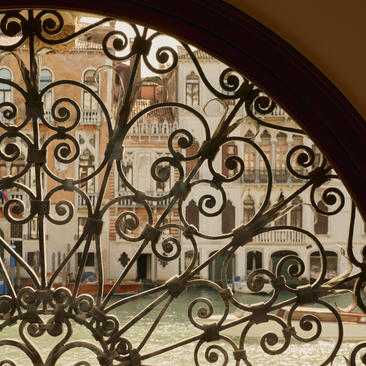 安缦威尼斯酒店大运河套房起居室内，装饰精美的铁艺栏杆展现优雅的螺旋纹饰设计。