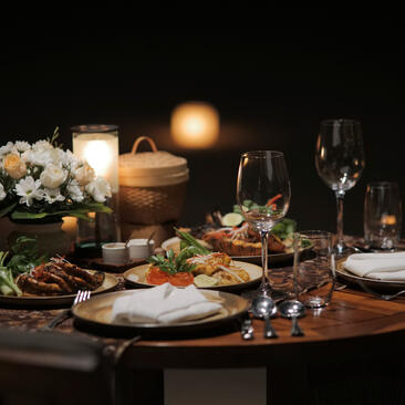 Man seated at candlelit dining table set for dinner at Aman Villas at Nusa Dua, Indonesia.