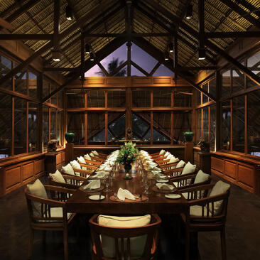 Amandari resort's dining venue with soaring wooden beams, round table set for guests, and views into the Ubud landscape.