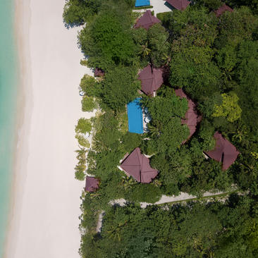 Villa with plunge pool nestled among tropical vegetation at Amanpulo resort, Philippines, aerial view.