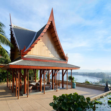 Thai-style pavilion at Amanpuri resort with peaked red roof overlooking coastal waters.