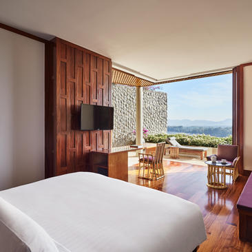 安缦璞瑞度假村的主卧室，配有宽敞床铺、木质特色墙面及远眺山景的落地窗。