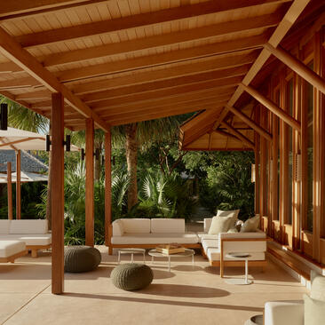 Outdoor terrace at Amanyara with wooden pergola, lounge seating and tropical garden views.