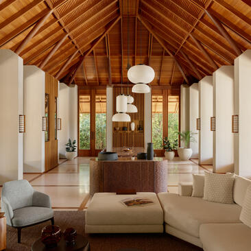 Amanyara villa lounge with pitched wooden ceiling, cream seating and natural light from floor-to-ceiling windows.