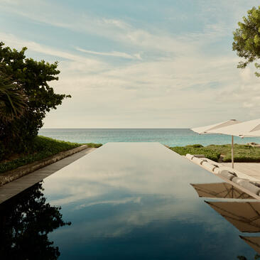 Infinity pool at Amanyara villa merging with turquoise waters and Caribbean coastline.