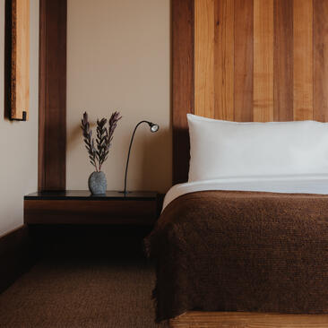 Deluxe suite at Amangani with bed, wooden headboard and bedside table with fresh flowers.