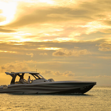 Captain at helm of speedboat during sunset at Amanpuri resort, Thailand.