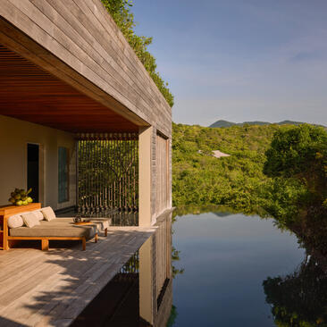 Forest wellness pool villa with wooden deck overlooking serene water at Amanoi, Vietnam.