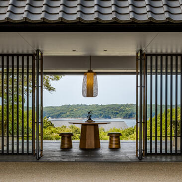 Amanemu's resort entrance lobby with open doors framing a coastal landscape view and ceramic vessels on display.