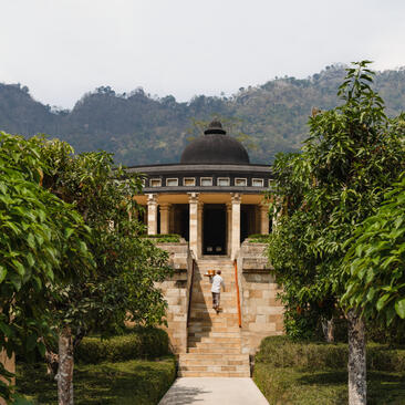 Pavilion with golden dome framed by verdant gardens at Amanjiwo resort, Java, Indonesia.