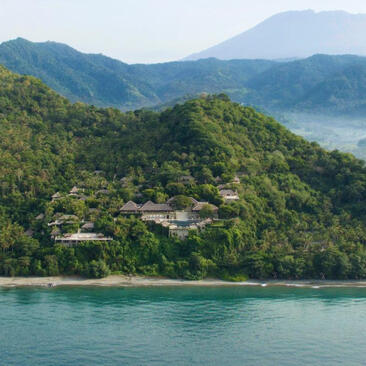 Amankila resort overlooking turquoise waters and forested hillsides in Bali, Indonesia.