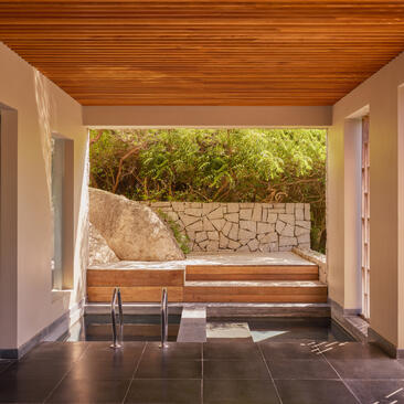Interior pool villa at Amanoi with wooden bench overlooking private pool and garden.