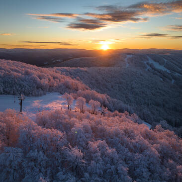 Sunrise over frost-covered forest at Aman New York, with golden light illuminating rolling mountains.