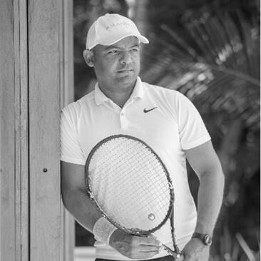 Jean Carlos holding a tennis racket at Amanera resort, Dominican Republic, black and white photograph.