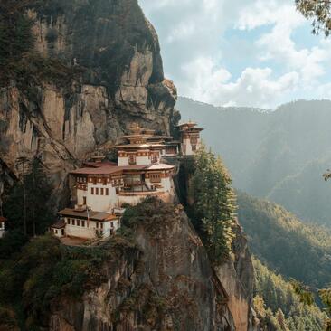 Taktsang Monastery perched on a cliff above Paro valley, with Amankora nearby in Bhutan's mountains.