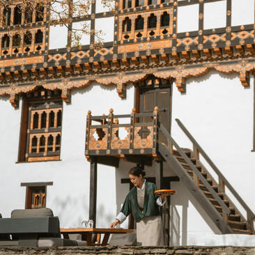 Ornate wooden balcony and carved window frames of a traditional Bhutanese structure at Amankora, Punakha.