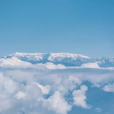 Snow-capped Himalayan peaks rising above clouds near Amankora, Punakha.