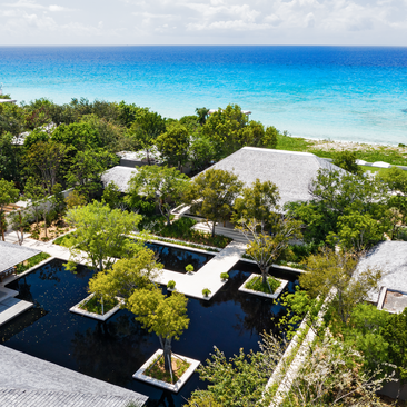 Four-bedroom villa with beachfront sala at Amanyara, Turks and Caicos, surrounded by tropical vegetation and turquoise waters.