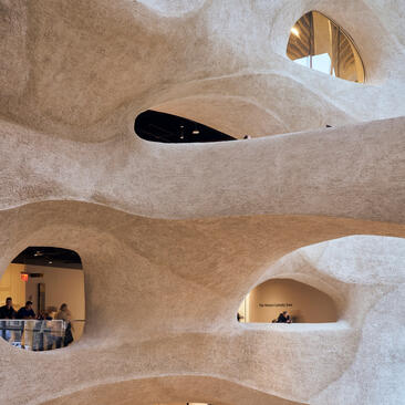 Curved cream stone walls with arched alcoves at Aman New York, featuring warm golden lighting.