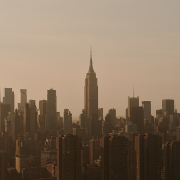 Aerial view of Manhattan's skyline at Aman New York, with the Chrysler Building rising above surrounding skyscrapers in warm afternoon light.
