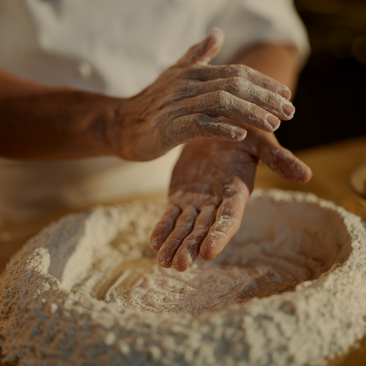 Hands kneading pasta dough at Aman New York hotel.