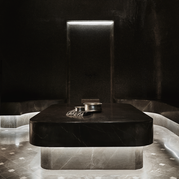 Spa hammam at Aman New York with dark stone basin and illuminated backdrop.