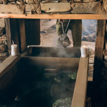 Hot stone bath filled with steaming water at Amankora, Bhutan, framed by wooden structure.