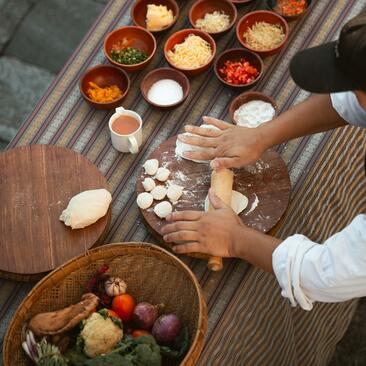 Chef preparing ingredients at Amankora's Punakha Lodge cooking class, with bowls of spices and vegetables arranged on wooden surface.