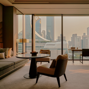 Principal suite at Aman Nai Lert Bangkok with floor-to-ceiling windows overlooking Bangkok's skyline, featuring modern furnishings and natural light.