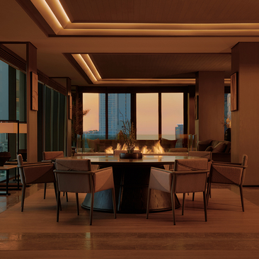 Aman Suite dining area at Aman Nai Lert Bangkok with round table, chairs, and city views through floor-to-ceiling windows.